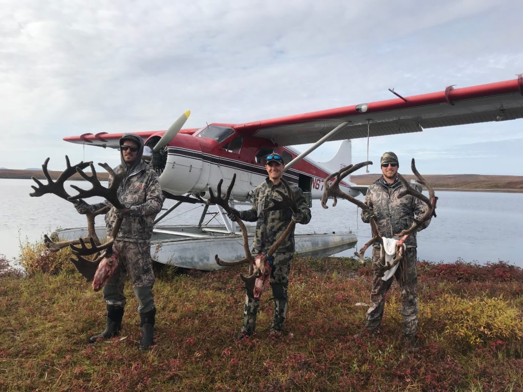 A happy group of three unguided caribou hunters getting ready to be flown out of the field in a float plane.