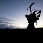 Silhouette hunter packing out a caribou